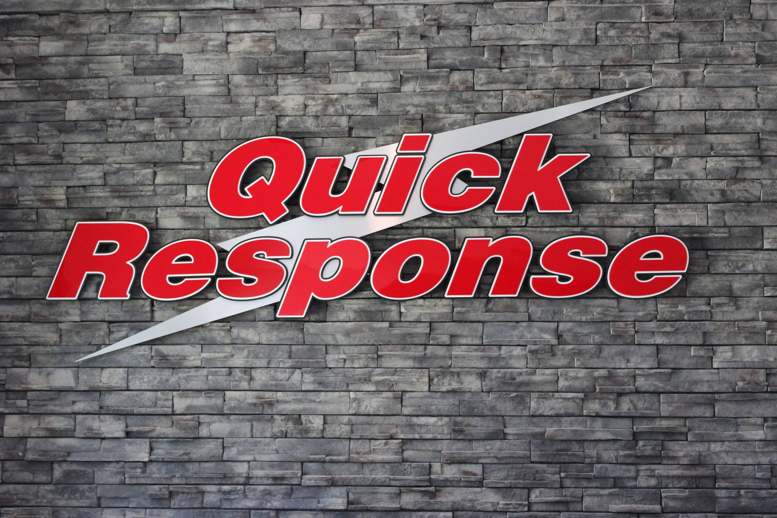 The Quick Response Restoration logo: red text with a white lightning bolt attached to a gray brick wall